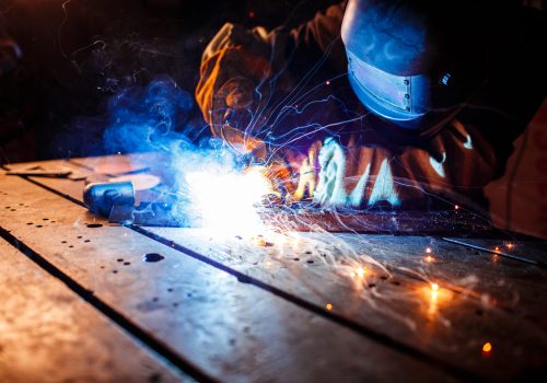Worker cutting metal with plasma equipment on plant.